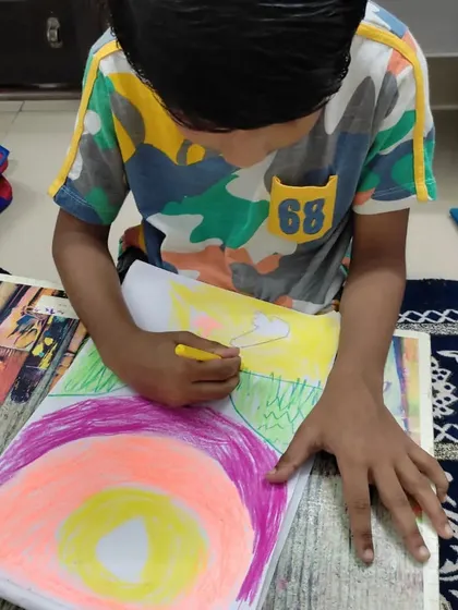 A young boy works with oil pastels to create a colorful sunset. This medium is perfect for kids to learn about blending and layering colors in a fun, direct way.