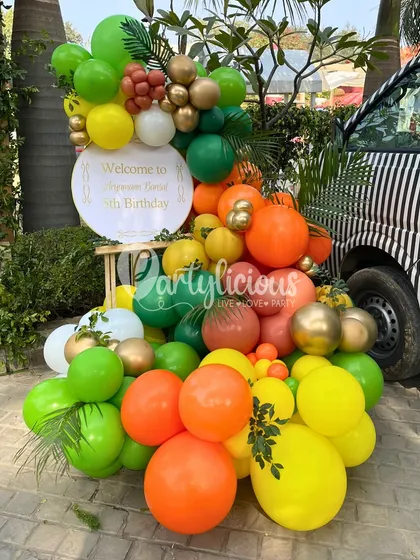 A vibrant welcome to a 5th birthday celebration. This colorful balloon arrangement, featuring a personalized sign, was placed next to a zebra-striped car to perfectly match the jungle party theme.