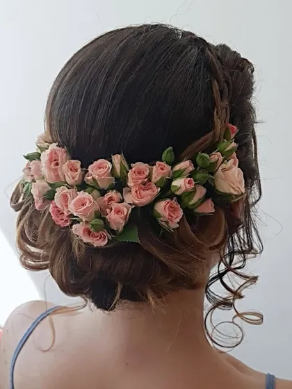 A soft and romantic updo featuring a crown of fresh pink roses. This is a lovely choice for a daytime event or an engagement party.