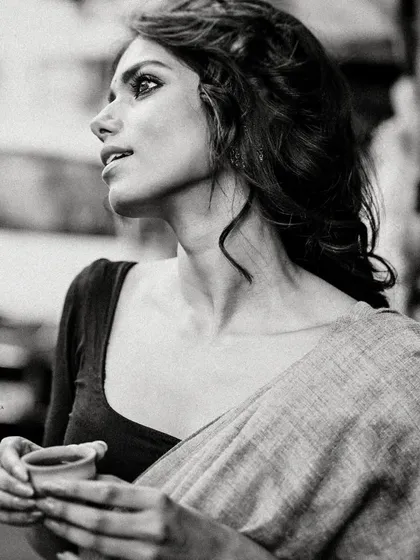 A black and white street portrait of a model in a saree, holding a traditional clay 'bhar' of tea. This shot captures a slice of everyday Kolkata life with a touch of cinematic grace.