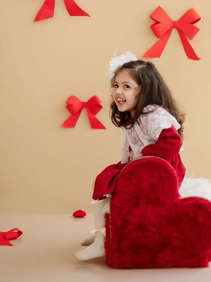 A playful, sideways glance from this little Valentine, sitting on a big red heart-shaped cushion.