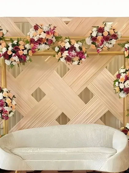 A minimalist yet elegant stage with a woven, textured backdrop. The design is accented with carefully placed bouquets of peach and burgundy flowers for a touch of color.