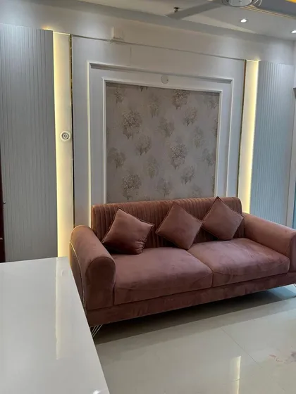 Here, we used a combination of fluted wall panels, soft backlighting, and a delicate floral wallpaper to create a feature wall. This design element serves as a beautiful backdrop for the plush pink sofa, adding texture, depth, and a touch of romance to the living room.