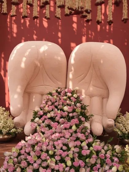A close-up of the hand-shaped seating, showcasing the detail of the sculpture and the abundance of fresh pink and white roses.