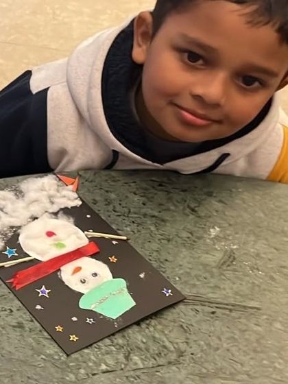 This young artist is proud of the snowman card he created using cotton, buttons, and paper. Our winter craft sessions are perfect for celebrating the cozy season.