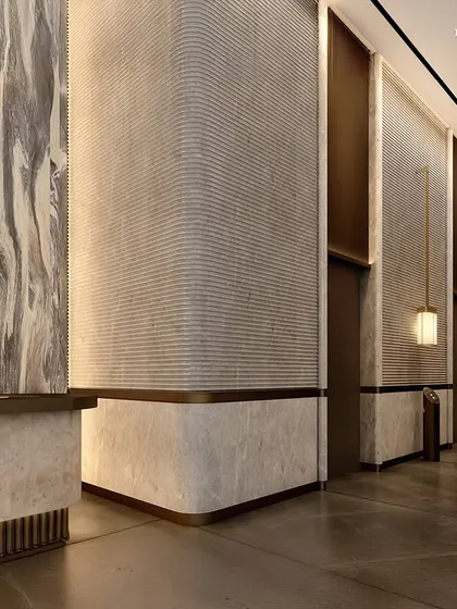 The elevator lobby of the commercial tower is a bold interplay of form, light, and proportion. The material palette draws from natural finishes, with textured stone walls and brass accents creating a space that feels both strong and serene.