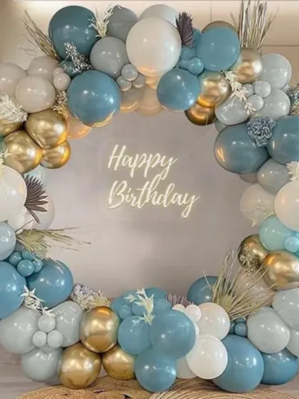 A sophisticated balloon hoop in dusty blue, white, and gold. This elegant arrangement is accented with pampas grass and a 'Happy Birthday' neon sign for a modern, chic look.