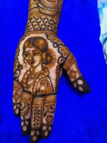 A close-up of the bride's portrait from a traditional Maharashtrian design. The fine lines and shading capture her serene expression, making it a centerpiece of the henna.