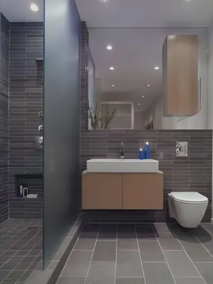 This bathroom features dark grey slate tiles in the shower and on the floor. A simple floating vanity and a large mirror help to keep the space feeling open and functional.