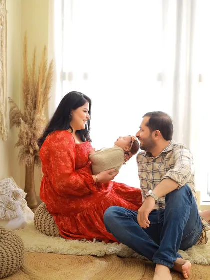 The father joins in, gazing at his newborn with adoration. This candid-style shot captures a genuine moment of connection between the new family.