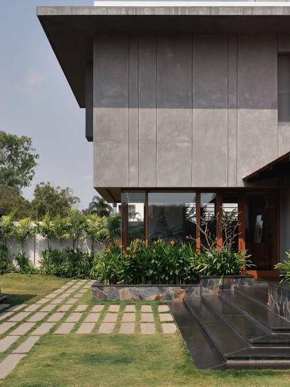 The home's exterior combines board-formed concrete textures with clean white walls and large overhangs, creating a distinctly modern tropical aesthetic.