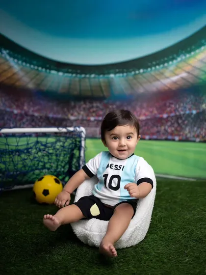 Another adorable pose from the football-themed baby shoot, showing off the complete setup.