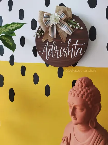 The "Adrishta" name plaque styled next to a terracotta Buddha statue in our studio, showing how our art complements a space of peace and tranquility.