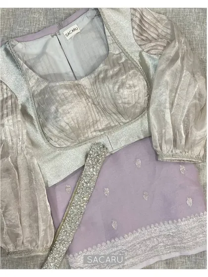 We enjoy giving classic silhouettes a modern interpretation. This blouse combines two different silver jari fabrics, with pleated details and exaggerated organza sleeves for a contemporary yet elegant statement.