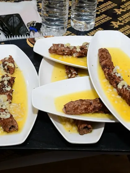 A tray full of our signature Butter Garlic Seekh, ready to be served. Each plate is generously topped with melted butter and chopped garlic.