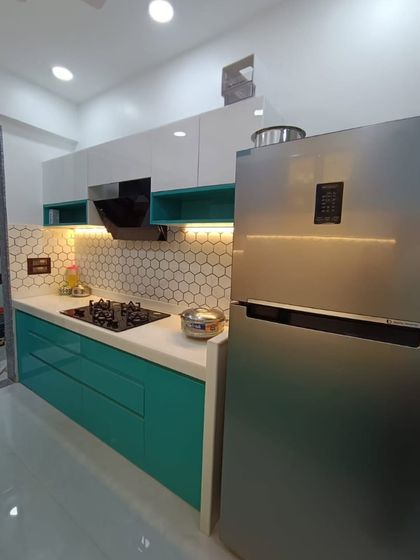 A straight-on view of the teal kitchen, showing the placement of the chimney and hob. The open shelves in a matching teal add a touch of color to the upper white cabinets.