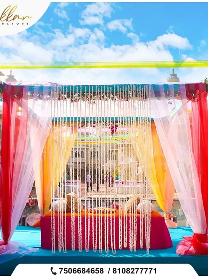 A colorful poolside mandap with bright red and sheer white drapes. This setup is perfect for a vibrant daytime wedding ceremony at a destination like Lonavala.