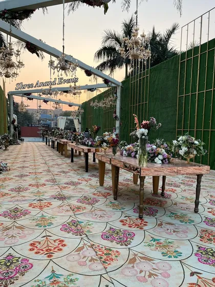 A long dining table setup in an outdoor venue at sunset, showcasing the beautiful floral arrangements and chandeliers before the night begins.