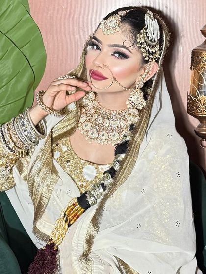 A stunning Walima look in white and gold. The makeup is bold and glamorous, with a deep red lip.