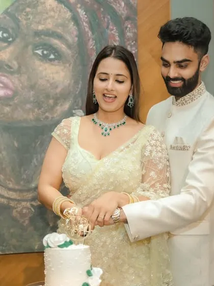 A joyous cake-cutting moment during an indoor engagement celebration in Pune. The couple's happiness is the focus, framed by modern decor and a beautiful piece of art, capturing the celebratory spirit of the occasion.