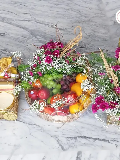 This image shows a coordinated set of gifts, including a fresh fruit basket and a dry fruit hamper, perfect for wedding celebrations.