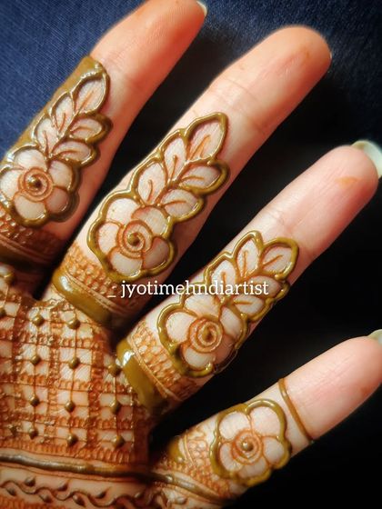 A close-up of a floral cutwork design on the fingers, showing the technique of leaving negative space to create the pattern.