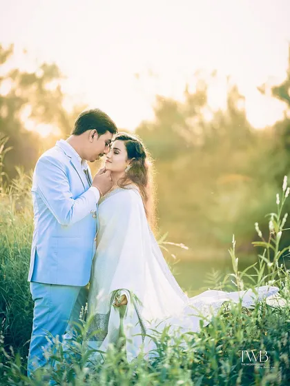 An intimate pose in a field during the golden hour. The warm sunlight filtering through creates a soft, romantic atmosphere, perfect for a dreamy and classic pre-wedding portrait.
