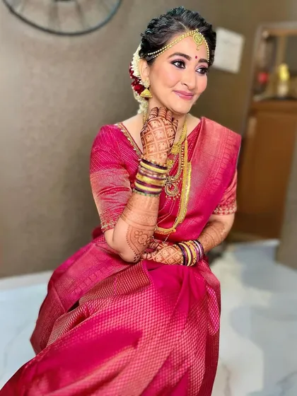 A beautiful bride in a vibrant pink Kanjivaram. The makeup features a classic winged liner and a matching pink lip, creating a look that is both traditional and glamorous.