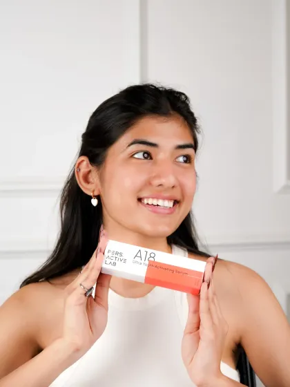 A bright, happy lifestyle portrait of a model holding the skincare product. Her genuine smile and radiant skin connect the brand with feelings of confidence and self-care.