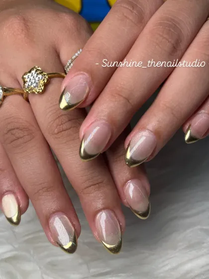 A classic gold chrome French manicure. The metallic gold tips on these almond-shaped nails create a look that is both elegant and eye-catching.
