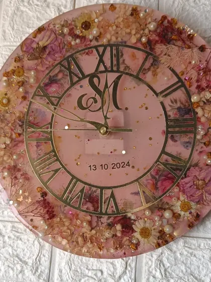 A top-down view of the 12-inch custom wall clock. The combination of preserved flowers, pearls, and a monogram makes this a truly personalized and elegant home decor item.