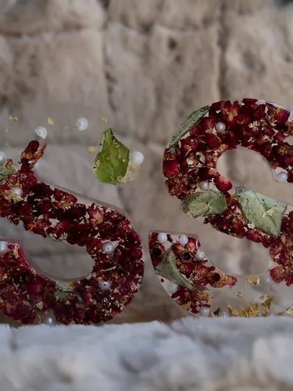 A pair of 'S' initial blocks made from crushed red rose petals, green leaves, and pearls. The texture and color are just beautiful.