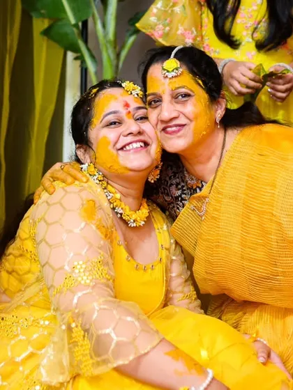A sweet hug between the bride, Neha, and her mother during the Haldi ceremony. Both are covered in yellow and happiness.