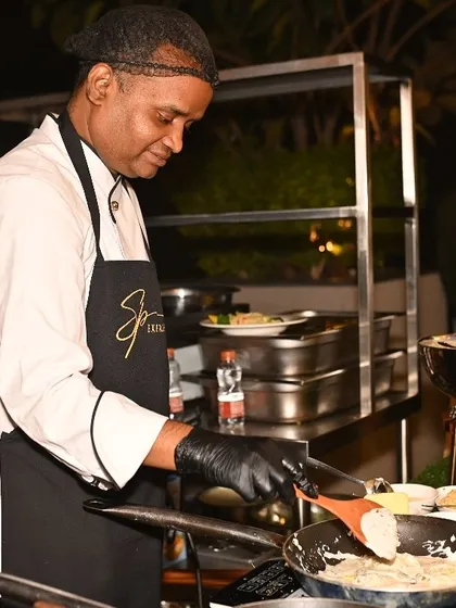Our chef expertly manages the pan at a live cooking station, showcasing the skill and focus that goes into creating delicious food on the spot.