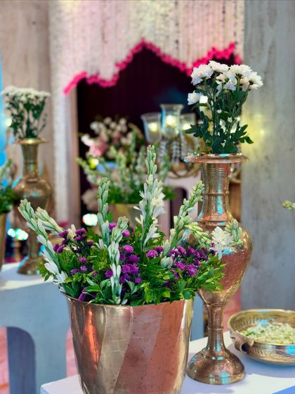 A close-up of fresh tuberoses and other flowers arranged in copper and brass pots, a simple yet elegant way to incorporate traditional elements.