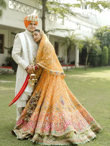 A portrait of togetherness. I styled the bride in a magnificent orange Rimple and Harpreet lehenga, rich with traditional embroidery, and coordinated the groom in a classic ivory sherwani for a timeless and royal couple's look.