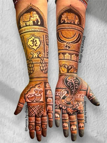 This bridal mehendi is a blend of spiritual and royal themes. It features the Om symbol, dhol drums, and majestic peacocks and elephants, covering the hands and forearms in dense patterns.