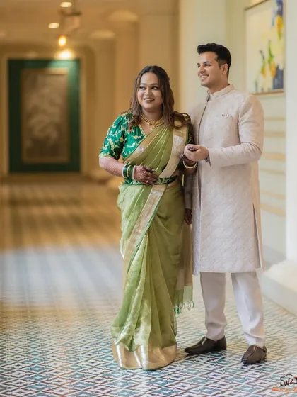 A full-length portrait of Shami and Udit, showcasing their classic and elegant engagement attire against a beautifully tiled floor.