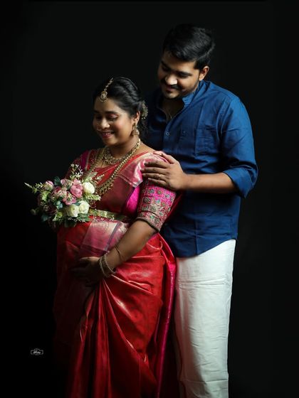 A sweet and intimate moment between a couple during their traditional studio photoshoot. The bouquet of flowers adds a touch of romance and celebration.