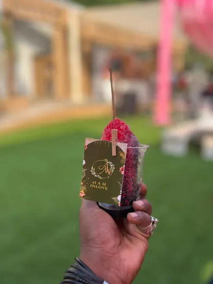 A guest holding a refreshing ice gola, a fun and nostalgic twist on a classic cocktail, personalized with a custom wedding tag.