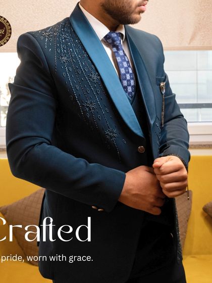 Crafted for pride, worn with grace. A model wearing the navy tuxedo, highlighting its sharp fit and the intricate lapel design.