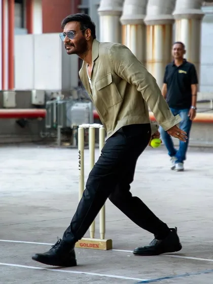 Ajay Devgn looking effortlessly cool during 'Maidaan' promotions at the IPL, captured mid-bowl in a stylish linen jacket.