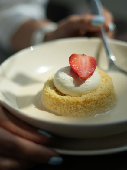 A beautifully lit shot of my Tres Leches cake, sitting in a pool of sweet milk and topped with a fresh strawberry.