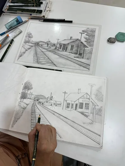 Learning perspective can seem tricky, but we break it down step by step. This student is doing a fantastic job capturing the depth of this railway station scene.