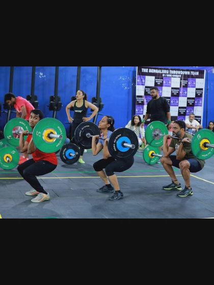 Athletes performing synchronized front squats during a team competition. This requires not only individual strength but also precise timing and teamwork.