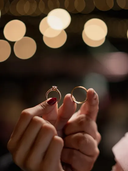 An artistic photo of the couple's hands holding their wedding rings against a backdrop of beautiful bokeh lights, creating a magical feel.