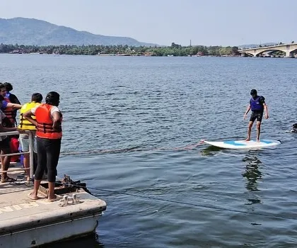 An instructor teaches a student how to balance on a paddleboard from the dock at our Karwar center.