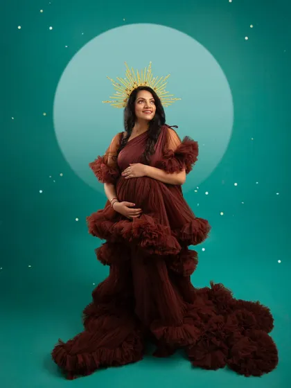 A celestial goddess. Crowned with a golden halo, the mother-to-be glows against a starry teal backdrop, looking powerful and serene.
