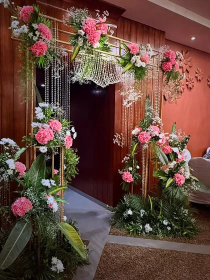 A beautiful entrance arch decorated with pink and white carnations and hanging crystal strings. This design creates a delicate and romantic passageway for guests entering the celebration.