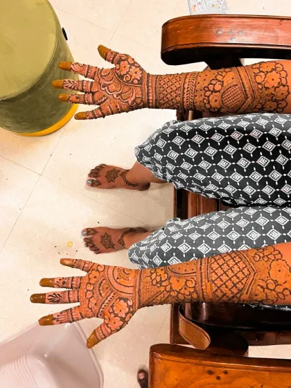 A complete bridal mehndi package includes detailed work on both hands and feet, as shown on this happy bride relaxing after her session.